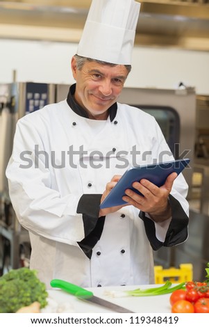 Chef using digital tablet and smiling in the kitchen