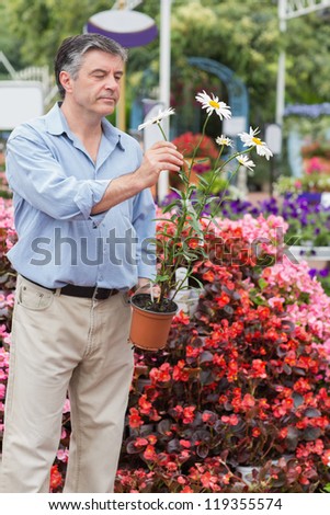 Man holding a flower and looking at it while smiling