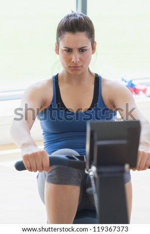 Focused woman at the rowing machine in the gym