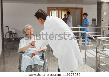 Old woman sitting on a wheelchair in a hospital while talking with the doctor