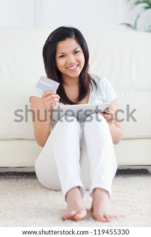 Woman holds a card and plays with a tactile tablet in a living room