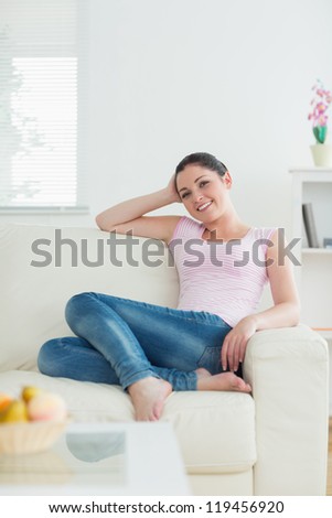 Relaxing woman sitting on the couch in a living room and smiling
