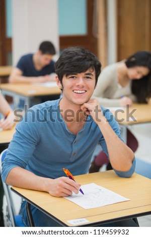 Student looking up and smiling during exam in exam hall in college
