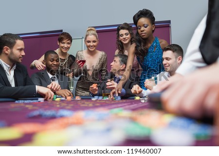 People standing and sitting at the table enjoying roulette