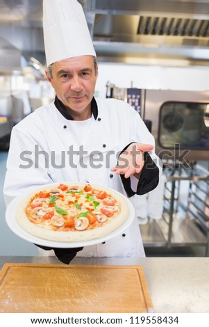 Cook presenting his pizza while smiling