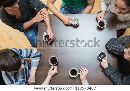 Students sitting around table drinking coffee in college cafe