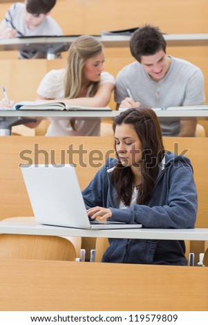 Student using laptop to take notes in lecture hall
