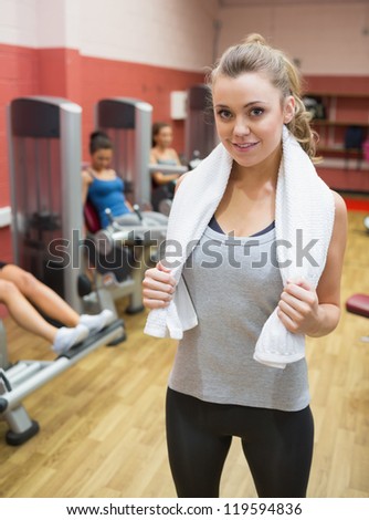 Woman with towel around neck in weights room in gym
