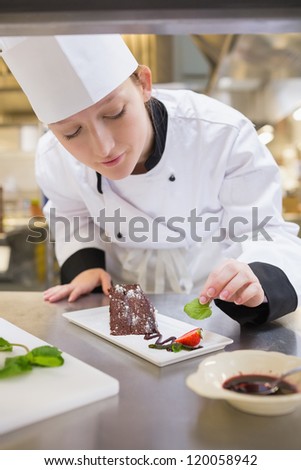 Female chef putting mint with chocolate cake in the kitchen