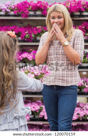 Child presenting flowers to her surprised mother in garden center