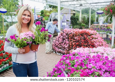 Blonde female customer in garden center while holding flowers