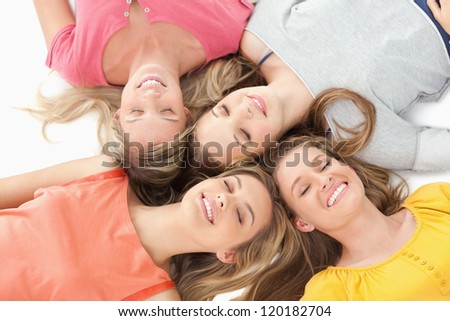 Four girls lying on the ground with their eyes closed and smiling