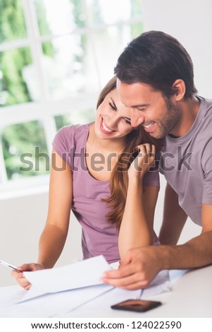 Smiling lovers in front of invoices in house