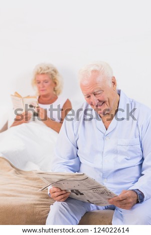 Smiling elderly couple reading on the bed in the bedroom