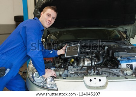 Portrait of confident mechanic by car holding digital tablet