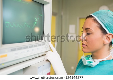 Smiling female surgeon standing next to a monitor in a surgery room