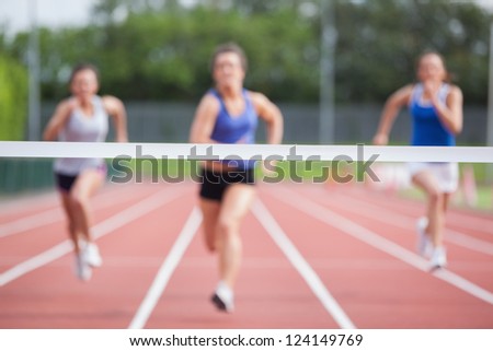 Female athletes racing towards finish line at track field