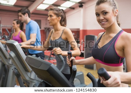 Smiling woman stepping on a step machine in gym