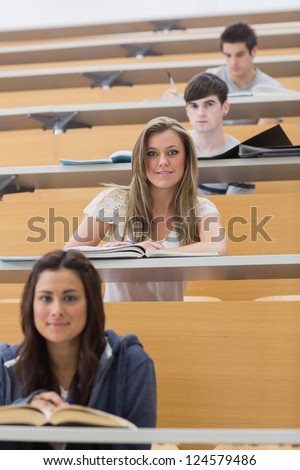 Students sitting while smiling in lecture hall in different rows