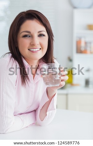 Portrait of young woman with glass of water in the kitchen