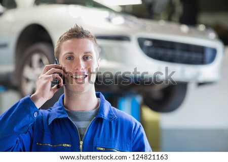 Portrait of young car mechanic using mobile phone