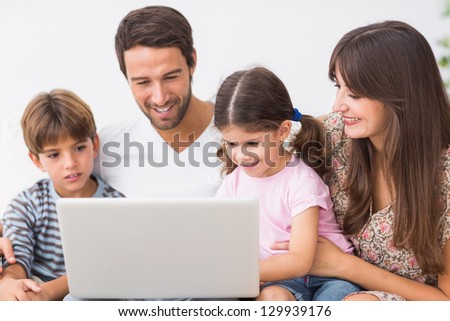 Smiling family on the couch using laptop