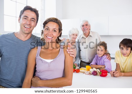 Mother and father standing by kitchen counter with family behind them