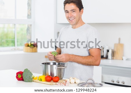 Smiling man making dinner in kitchen