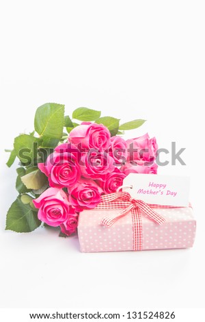 Bouquet of pink roses next to a gift with a  happy mothers day card on a white table