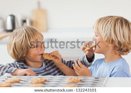 Brothers eating cookies together in the kitchen