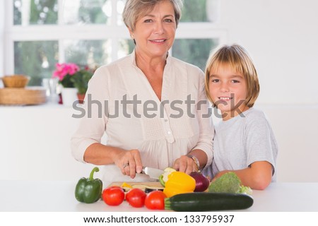 Grandmother cutting vegetables with her grandson in kitchen