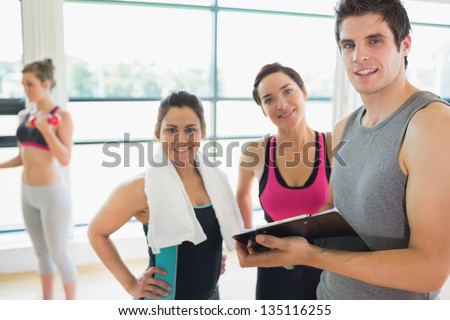 Trainer and women smiling in fitness studio