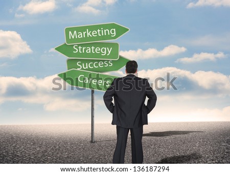 Businessman looking at signposts with marketing terms with bright blue sky