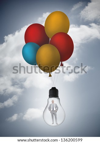 Businessman inside light bulb held by balloons in the sky with clouds