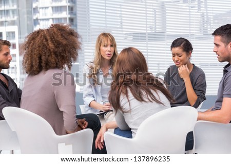 Woman crying during therapy session with other people and therapist