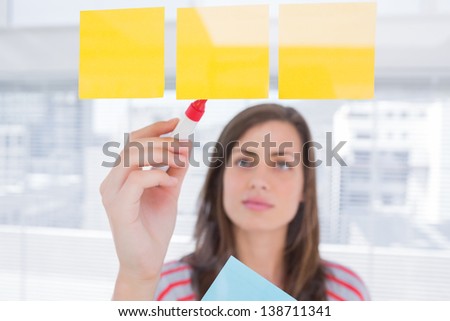 Woman writing on sticky note in creative office