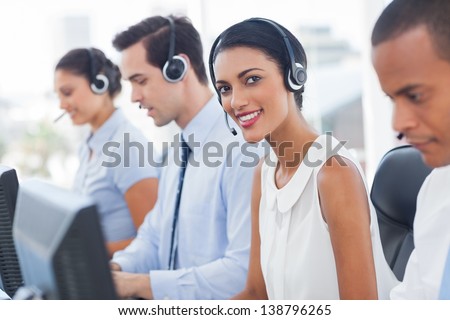 Smiling agent with colleagues sitting next to her