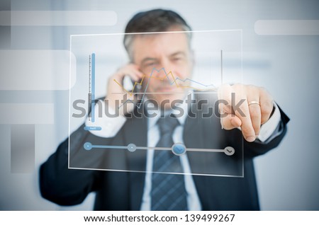 Businessman on the phone using futuristic touchscreen to view graph