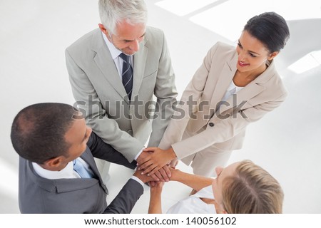 United team standing together and piling up their hands in the workplace