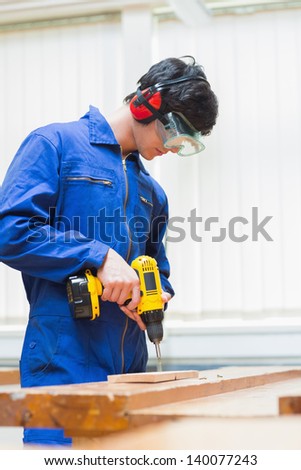 Student of a woodworking class learning to drill with nails in wooden boards