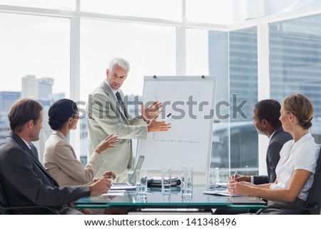 Businessman in front of a growing chart during a meeting with concentrated colleagues