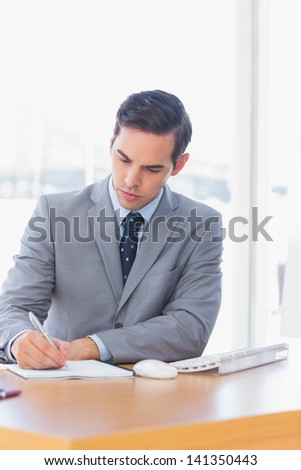 Focused businessman writing at his desk in the office