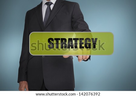 Businessman touching the word strategy written on green tag on blue background