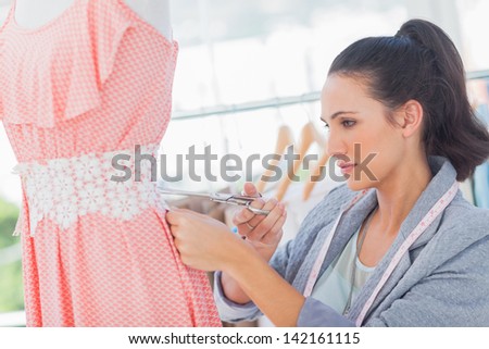 Attractive fashion designer cutting dress with scissors