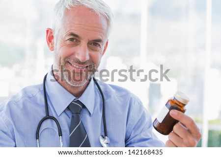 Smiling doctor holding medicine jar and looking at camera