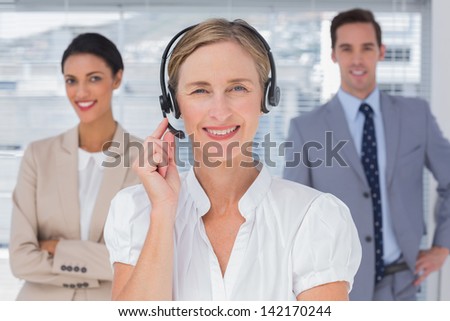 Woman with headset standing in front of business people