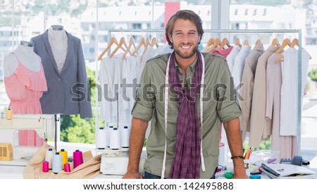 Fashion designer leaning on his desk and smiling to the camera