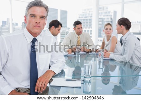 Serious businessman in a meeting with colleagues working behind