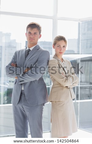Business colleagues standing back to back in their modern office