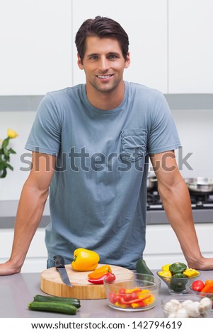 Attractive man standing in his kitchen in front of sliced vegetables